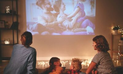 Família assiste a filme projetado na parede de sala escura