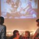 Família assiste a filme projetado na parede de sala escura