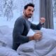 Homem barbudo em camisa de manga longa sentado na cama, segurando caneca, com paisagem nevada