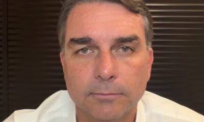 Close-up do senador Flávio Bolsonaro, com expressão neutra, olhando diretamente para frente