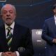 Lula fala em debate televisivo, Bolsonaro observa. Logos "Band", "ao vivo", "LULA", "2026" na tela