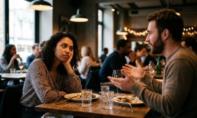 Mulher com rosto apoiado na mão parece entediada, enquanto homem fala em restaurante