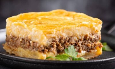 Fatia de escondidinho: purê de batata, carne moída, queijo em prato escuro