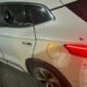 SUV branco com vidros laterais quebrados, amassados e marcas de tiros na lataria do veículo