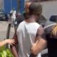 Policiais escoltam homem em camiseta branca durante prisão em via pública