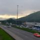 Rodovia com tráfego intenso e congestionamento, veículos parados, montanhas e céu nublado ao fundo