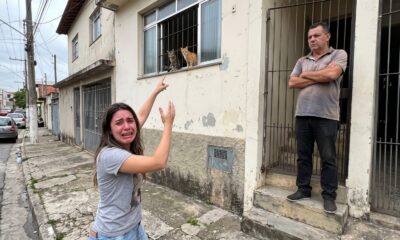 Mulher chorando aponta para gatos em janela, homem bloqueia entrada