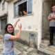 Mulher chorando aponta para gatos em janela, homem bloqueia entrada
