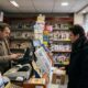 Funcionário e cliente em loja francesa com displays da loteria e produtos de tabaco