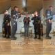 Policiais fardados comemoram aniversário com mulher em casa, com abraços, palmas e bolo
