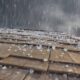 Telhado de telhas de madeira com granizo e chuva sob céu escuro e nublado