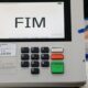 Urna eletrônica exibe "FIM" na tela, teclado numérico e botões Branco, Corrige, Confirma.