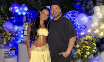 Casal sorridente Rayane Figliuzzi e Belo em festa com balões azuis e flores amarelas