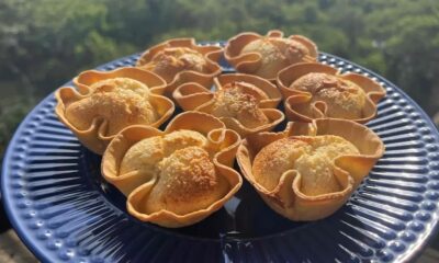 Cestinhas de coco assadas em forma de flor, com recheio claro e casquinha dourada, sobre prato azul