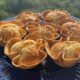 Cestinhas de coco assadas em forma de flor, com recheio claro e casquinha dourada, sobre prato azul
