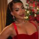A cantora Marvvila sorri para a câmera com vestido vermelho e fundo de Natal