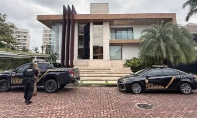 Viaturas da Polícia Federal e agentes em frente a uma residência moderna de alto padrão