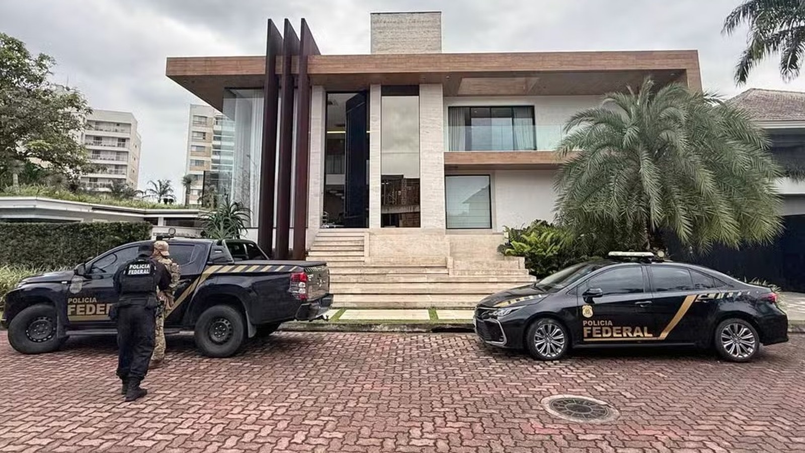 Viaturas da Polícia Federal e agentes em frente a uma residência moderna de alto padrão