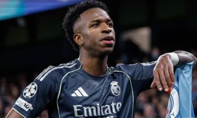 Jogador Vini Jr. de camisa Real Madrid, patches, "Emirate", braço em camisa Manchester City