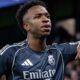 Jogador Vini Jr. de camisa Real Madrid, patches, "Emirate", braço em camisa Manchester City