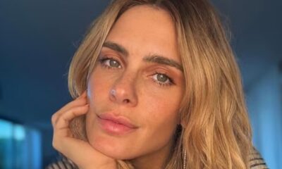 Close-up de Carolina Dieckmann, cabelo loiro, olhos claros, com a mão no rosto