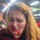 Mulher jovem chora com boca ensanguentada, enquanto homem uniformizado a observa em estação