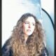 Retrato de Renata Alves Mietto, mulher com cabelo cacheado olhando para o lado direito