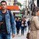 Homem sério com celular na mão e mulher olhando para o smartphone caminhando em rua movimentada