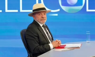 Luiz Inácio Lula da Silva de terno, gravata e chapéu sentado em estúdio de TV