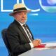 Luiz Inácio Lula da Silva de terno, gravata e chapéu sentado em estúdio de TV