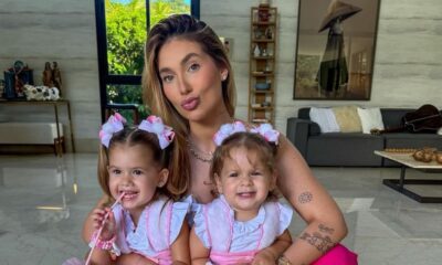 Mulher sorridente e duas meninas pequenas, vestindo roupas rosa idênticas e laços de cabelo combinando