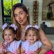 Mulher sorridente e duas meninas pequenas, vestindo roupas rosa idênticas e laços de cabelo combinando
