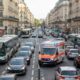 Ambulância branca com “NOTARZT” e luzes azuis em rua movimentada com carros e ônibus