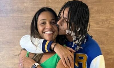 Rapper Oruam beija o rosto sorridente da mãe, Márcia Gama, com fundo de madeira