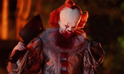 Pennywise, o palhaço de IT, com maquiagem sangrenta e um cutelo de açougueiro na mão