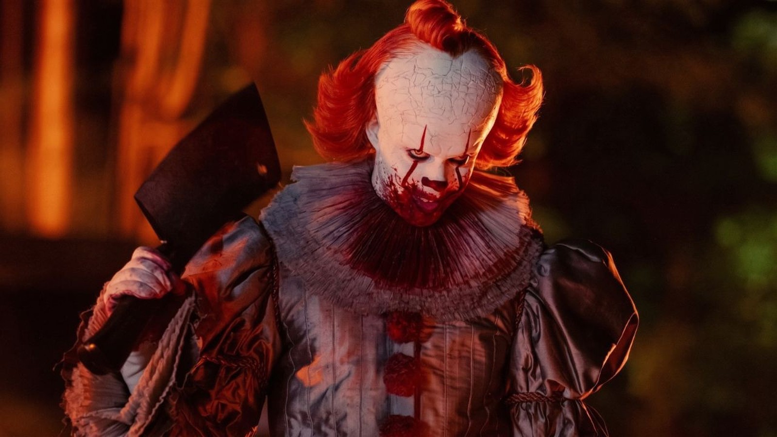 Pennywise, o palhaço de IT, com maquiagem sangrenta e um cutelo de açougueiro na mão