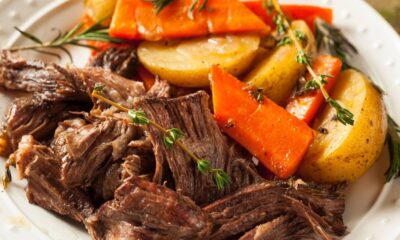 Prato com carne desfiada, batatas e cenouras assadas, guarnecido com alecrim e tomilho