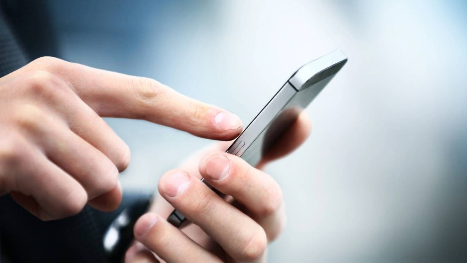 Mãos segurando um smartphone e um dedo indicador tocando a tela