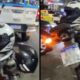 Parte traseira de uma motocicleta com dois capacetes e placa brasileira, com viatura policial ao fundo