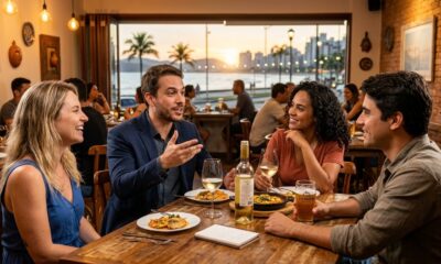 Quatro pessoas em restaurante conversando, com comida, vinho, cerveja Everbren e pôr do sol