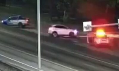 Vista aérea noturna de via expressa com carros, viatura policial e luzes piscando