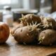 Maçã vermelha e batatas com brotos em uma tábua de madeira clara