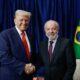Donald Trump e Luiz Inácio Lula da Silva sorriem e apertam as mãos, com bandeiras ao fundo