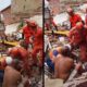 Bombeiros resgatam pessoas dos escombros de um prédio desabado, cercados por entulho e poeira