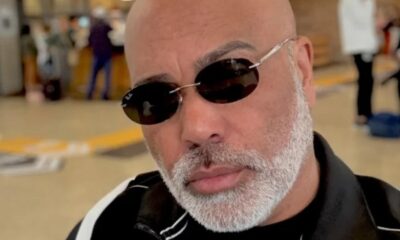 Close-up de homem careca com barba grisalha e óculos escuros Ray-Ban com '72'