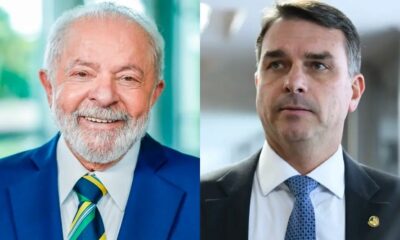 Luiz Inácio Lula da Silva sorrindo, e Flávio Bolsonaro, ambos de terno