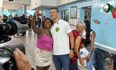 Douglas Ruas sorri em selfie com eleitora, usando camiseta com adesivo '22'