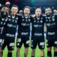 Seis jogadores do Santos sorriem e celebram em campo, vestindo uniformes pretos