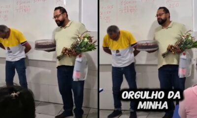 Dois homens em sala de aula, um curvado, outro com bolo e flores, texto ORGULHO DA MINHA