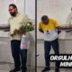 Dois homens em sala de aula, um curvado, outro com bolo e flores, texto ORGULHO DA MINHA